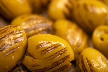 Green marinated olives, pitted, roasted on the grill. The texture of the surface. Close-up,...