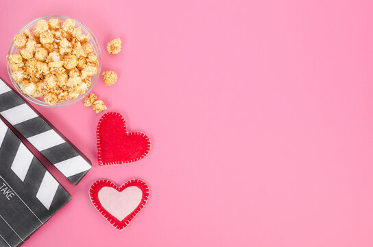 Valentine's Day movie concept. Movie clapperboard with hearts and caramel popcorn with copy space