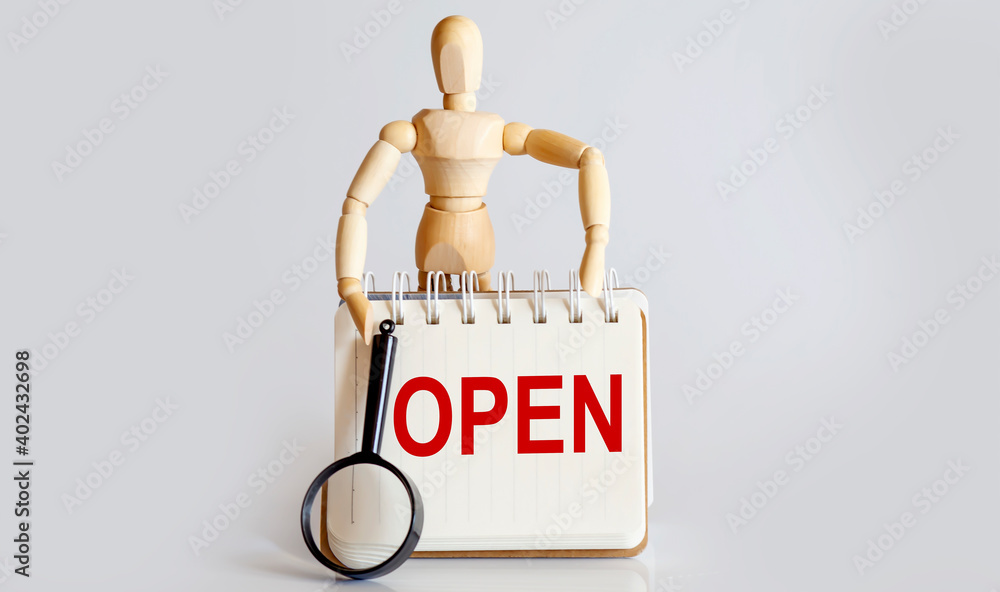 Poster wooden man shows with a hand to white notepad with text open