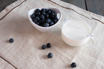 milk in a glass and blueberries in a cup