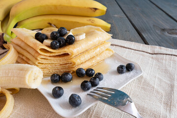 fresh bananas, blueberries, freshly baked pancakes poured with honey in a plate