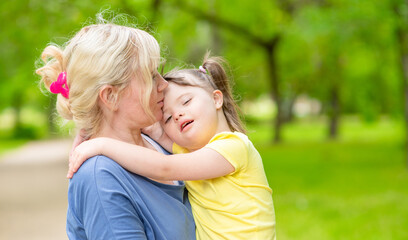 Happy family. Mom and her little daughter with syndrom down have a fun in summer park. Empty space...