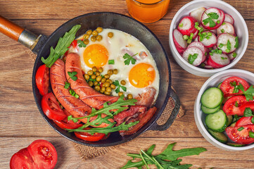 Traditional breakfast of scrambled eggs with sausages and fresh vegetable salad . The view from the top