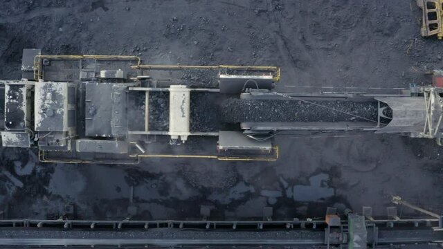 Drone/Aerial top down shot of ROM Raw Materials consisting of coal and rocks being transported via a conveyor belt into a crusher