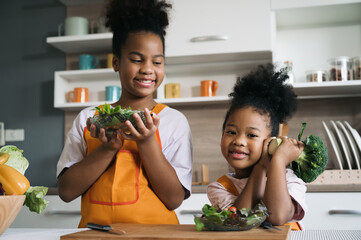 Happy sister black skin with salad on plate in kitchen 