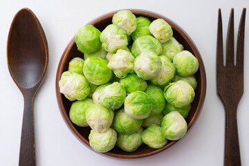 wooden fork and spoon on the table, between them green brussels sprouts in a wooden bowl