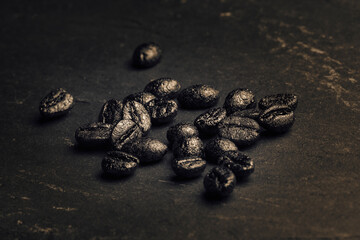 Granos de café torrefacto o torrado sobre superficie de piedra negra