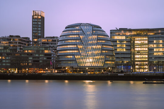 Night view of illuminated London City Hall across the River Thames
