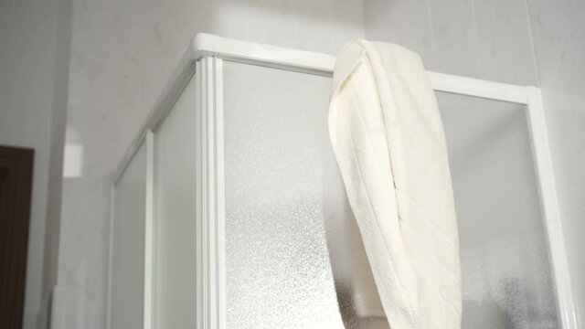Unrecognizable woman hanging towel on shower cabin. Lady taking douche in bathroom at home in the morning. Awakening hygiene concept.