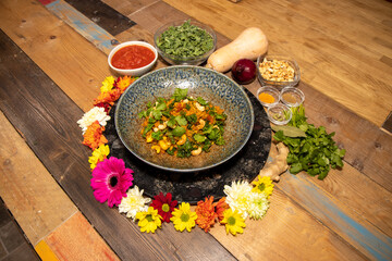 A delicious plate of Butternut Squash Biryani with cashew nuts surrounded by Indian flowers, spices and ingredients