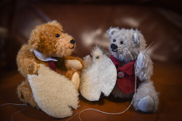 Two home made teddy bears sewing another teddy bear