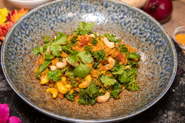 A delicious plate of Butternut Squash Biryani with cashew nuts on a wooden kitchen table or work top