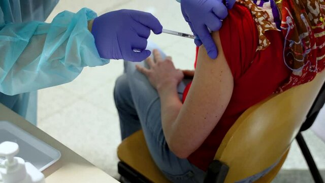 Woman is being vaccinated during COVID-19 vaccination program with the Pfizer BioNTech vaccine in Warsaw, Poland
