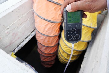 Construction supervisor hand holding gas detector device while commencing safety gas testing...