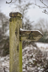 Snow covered signpost on footpath giving directions
