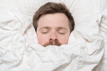 Cute, charming man asleep wrapped in a blanket. 