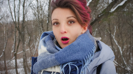 Close-up female portrait of glam rock style look of a beautiful girl with dark pink hair and mohawk wearing blue scarf