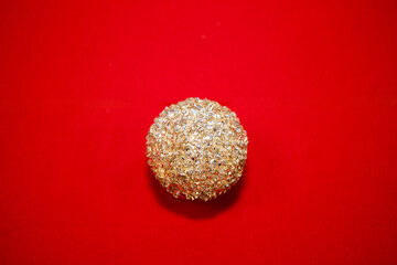 A Christmas golden ornament on a velvet red background