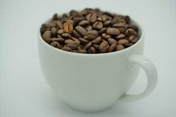 White cup of coffee filled with aromatic coffee beans with white background