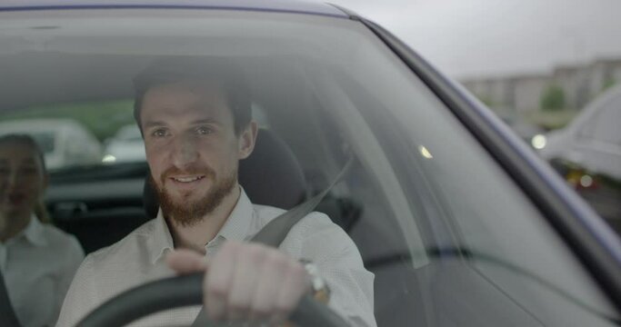Handsome Male taxi driver smiles and talks to his passenger inside the car