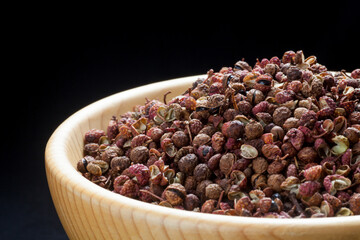 Sichuan pepper (zanthoxylum bungeanum) in a wooden bowl. Chinese prickly ash.