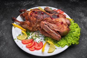 Roasted Christmas duck, on a white plate with vegetables, on a dark background