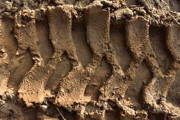 Footprint of wheel tread on the ground road. The trail from the tread of trucks wheels. Car tire tread imprint on sand, background, texture. Footprints rubber tyres from automobile