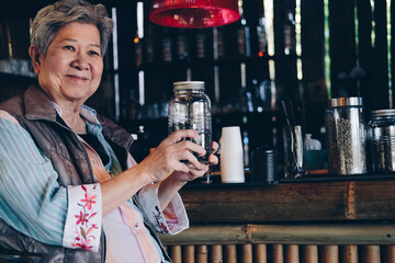 asian old elder woman elderly holding roasted coffee bean in cafe shop