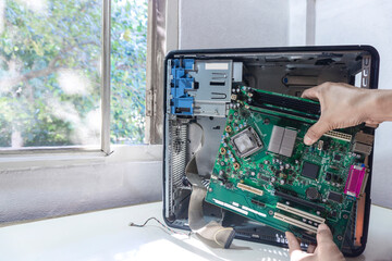 Young repairman technician fixing or upgrade mainboard on a case computer repairs pc computer in...