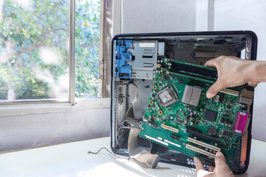 Young repairman technician fixing or upgrade mainboard on a case computer repairs pc computer in the service center.