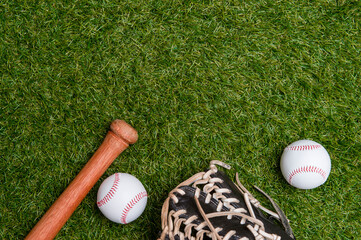 Baseball bat, glove and ball on green grass field.  Sport theme background with copy space for text and advertisment