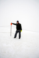 Man immersed in the mist on a snow-covered mountaintop with ski slopes.