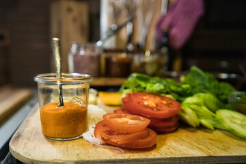 Chili Dip, Mayo Dip, geschnittene Tomaten, Kopfsalat, Gurken, frische Zutaten zum Kochen auf einem Holzbrett