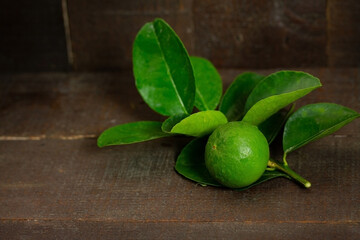 Fresh lime fruit and branches on the wooden background.