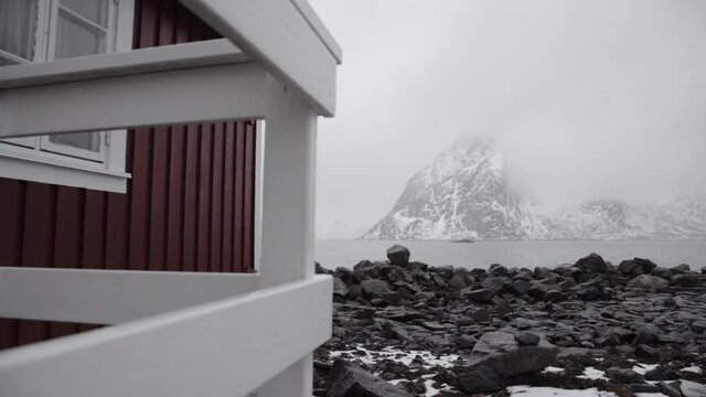 Fachada de casa n&oacute;rdica frente a playa de rocas negras