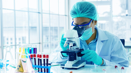 Scientist or doctor use microscope to test for the coronavirus (COVID 19). Or a new flu virus to...