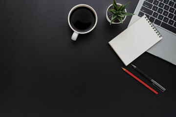 Top view above of Black office desk table with keyboard of laptop and notebook with equipment other...