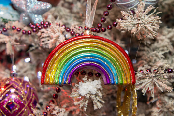 A Christmas ornament in the Shape of a rainbow on a festive Christmas tree