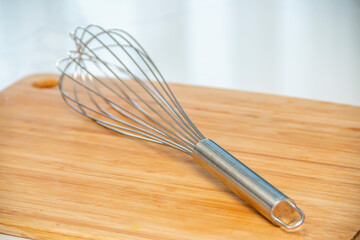 Metal whisk on a wooden cutting board