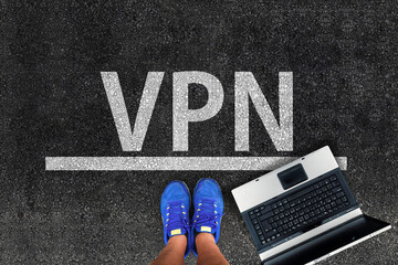 VPN , virtual private network. Legs in shoes standing next to laptop and word VPN