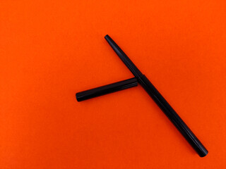 Kajal pencil with cap isolated on orange background.