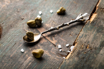 pickled capers on a dark wooden background. Edible flower buds of Capparis spinosa, caper bush or Flinders rose. Delicious ingredients for cooking