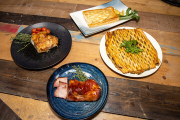 A selection or meat roasts and pies on a wooden background