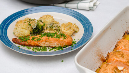Baked salmon, cauliflower and broccoli casserole served with chopped chives close up on a plate