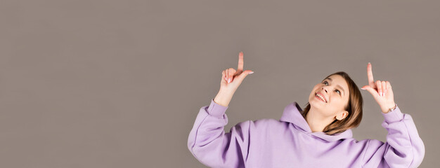 Happy woman pointing up with both hands isolated on a gray background