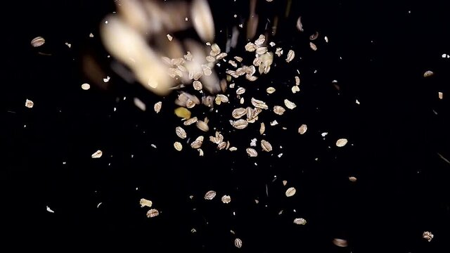 Pouring oat isolated on dark background close-up top view. Oatmeal is slowly spilling on the dark table. Slow motion video
