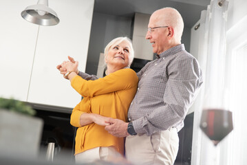Senior couple dancing and smiling at home