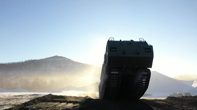 Military tracked all-terrain vehicle climbs the slope