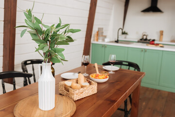 decorative plant in white vase on table with blurred vegetarian dinner on background in kitchen