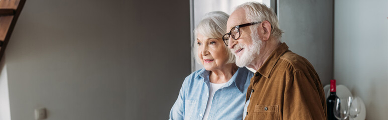 smiling senior couple looking away indoors, banner